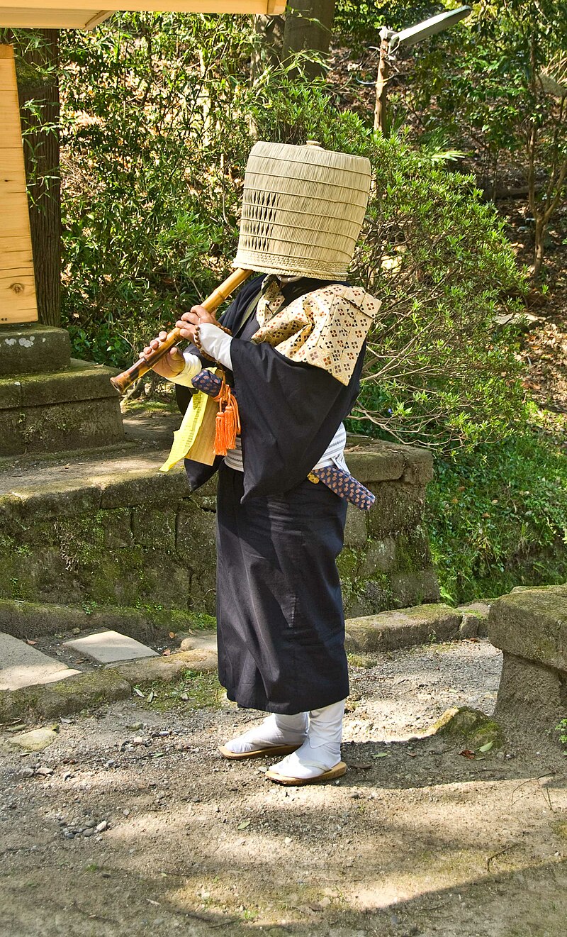 A komuso monk, with a basket over their head, playing the shakuhachi